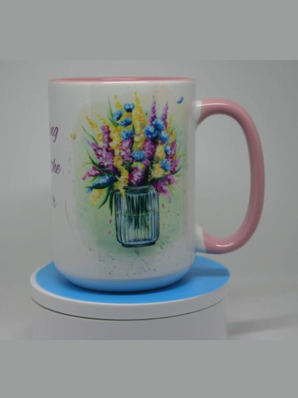 A mug with flowers in it sitting on top of a coaster.