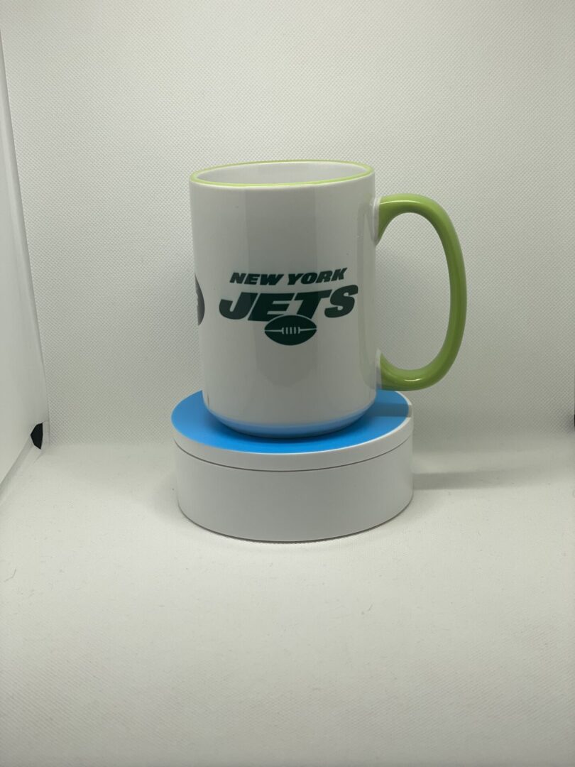 A white and green mug sitting on top of a blue coaster.