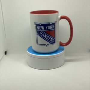 A red and white mug sitting on top of a coaster.