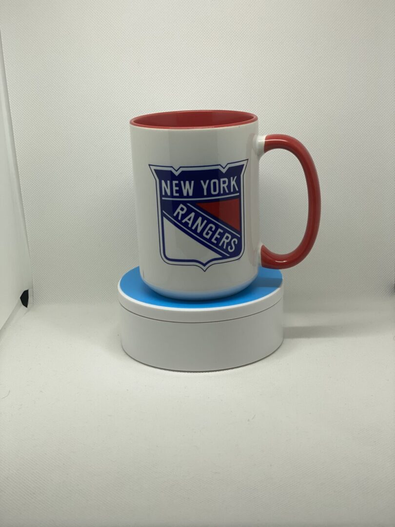 A red and white mug sitting on top of a coaster.