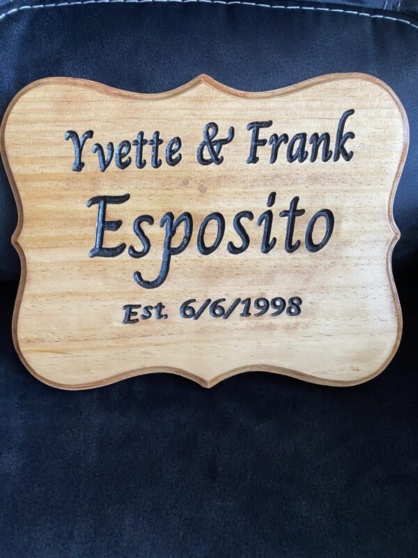 A wooden sign with the name of a couple and their wedding date.