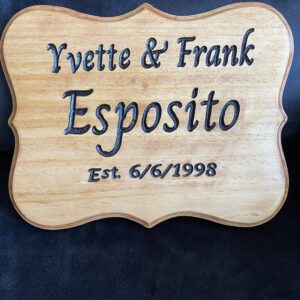 A wooden sign with the name of a couple and their wedding date.