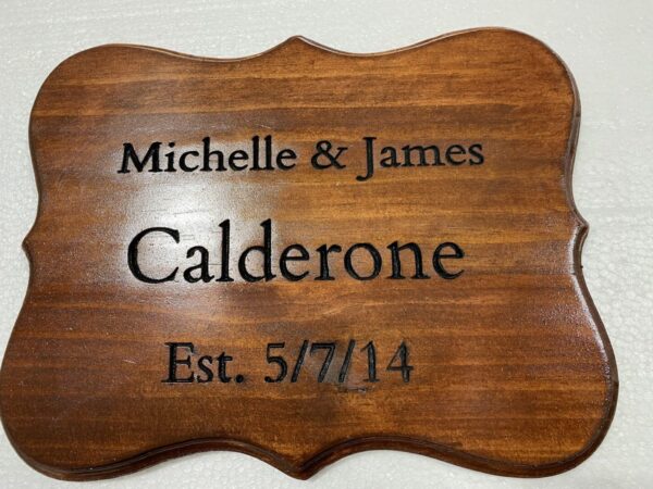 A wooden plaque with the name of a couple and their wedding date.