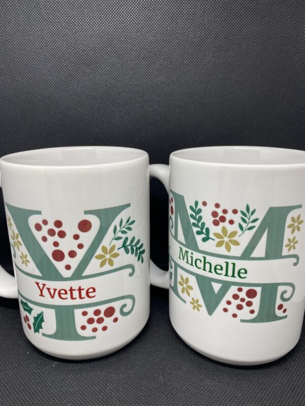 Two mugs with the same name and a couple of flowers on them.