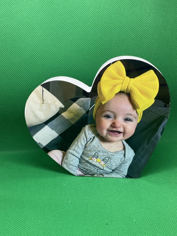 A baby with a yellow bow on its head.