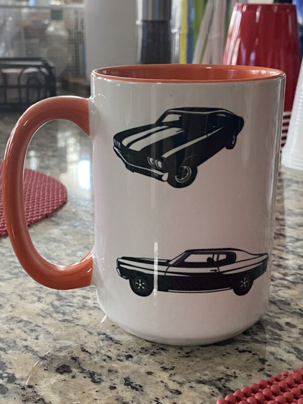 A coffee mug with two different cars on it.