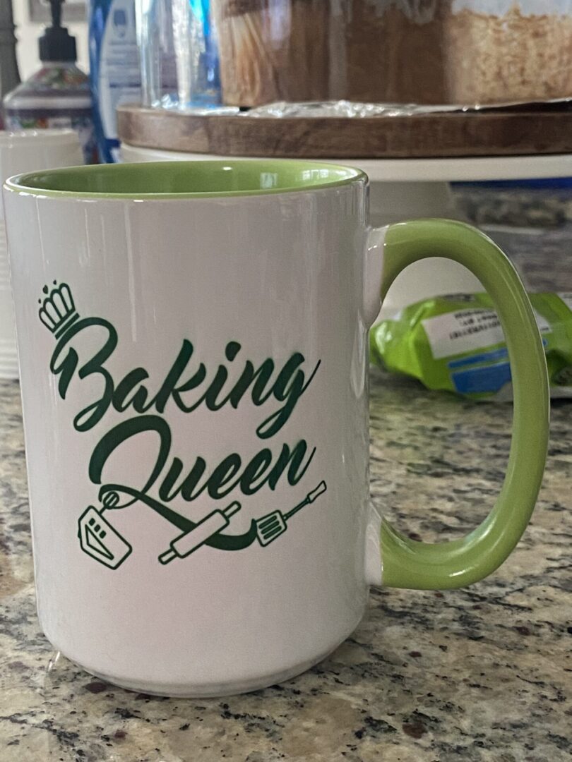 A coffee mug that says baking queen on it.