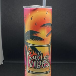 A tall cup with palm trees and sunset on it.