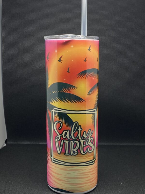 A tall cup with palm trees and sunset on it.