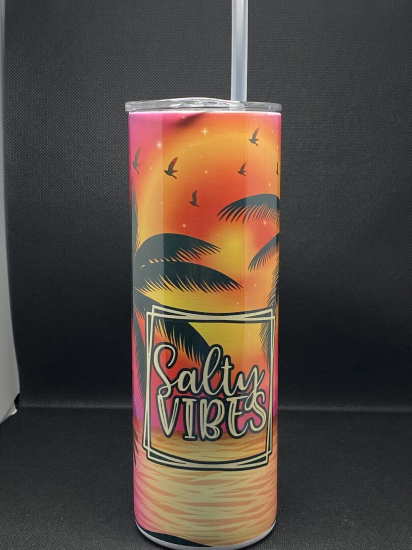 A tall cup with palm trees and sunset on it.