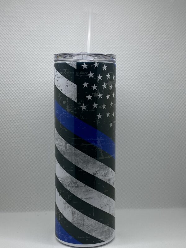 A tall skinny cup with the american flag and blue line on it.