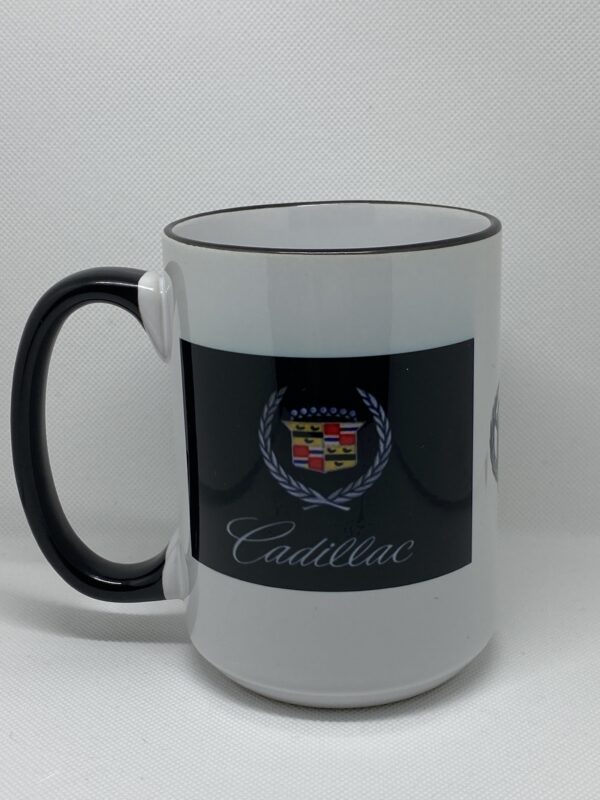 A white coffee mug with black rim and cadillac logo.