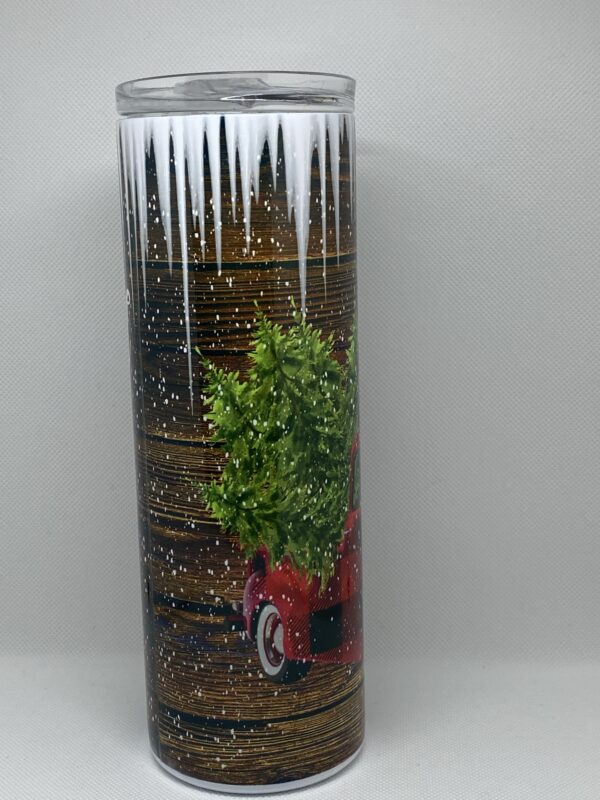 A candle with a picture of trees and a car.