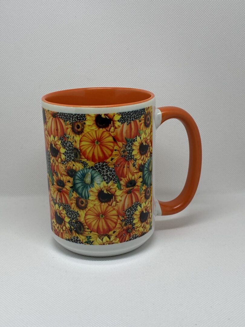 A coffee mug with an orange handle and a sunflower design.