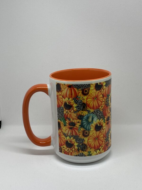 A coffee mug with an orange handle and a sunflower design.