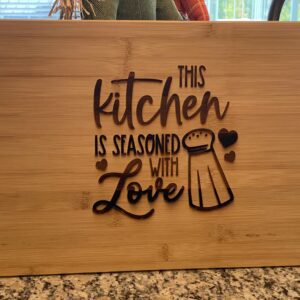 A cutting board with the words " this kitchen is seasoned with love ".