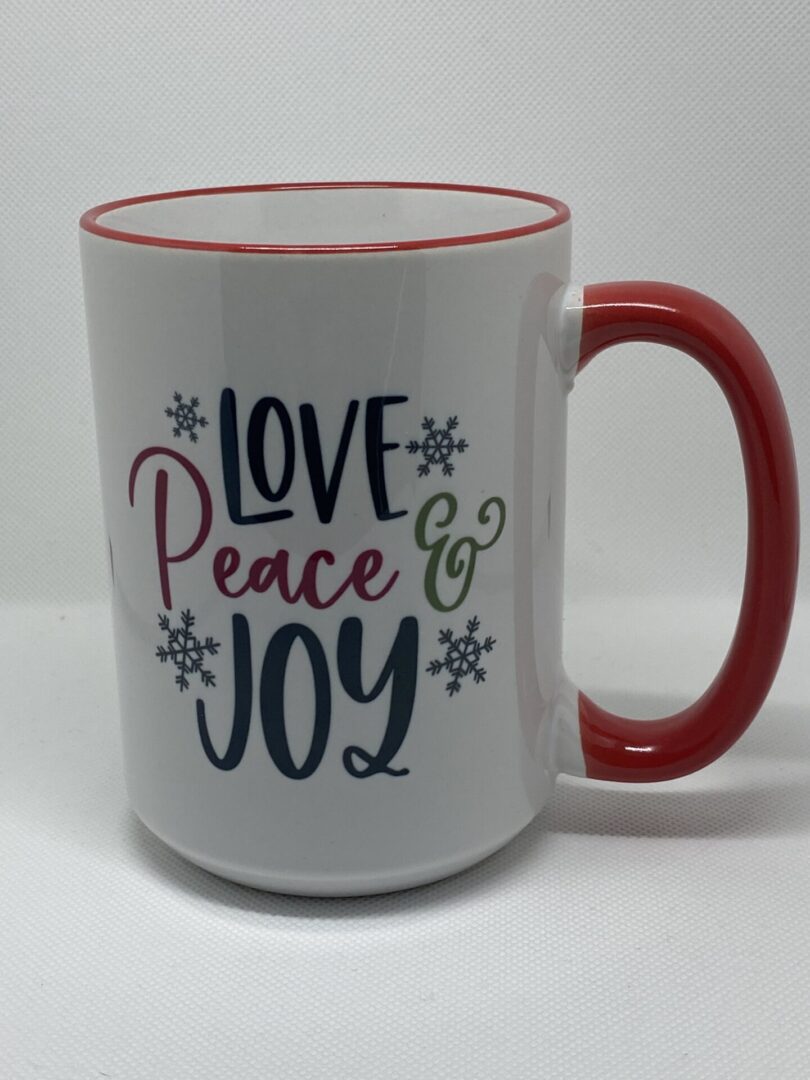 A coffee mug that says love peace and joy.