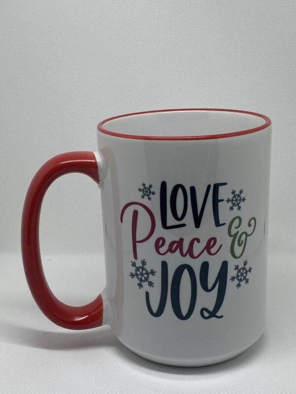 A coffee mug that says love peace and joy.