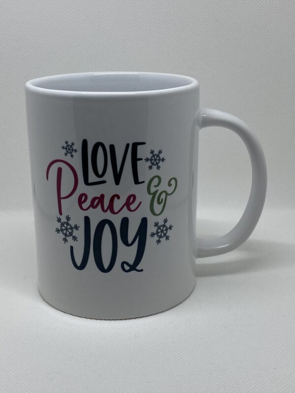 A white coffee mug with the words " love peace & joy ".