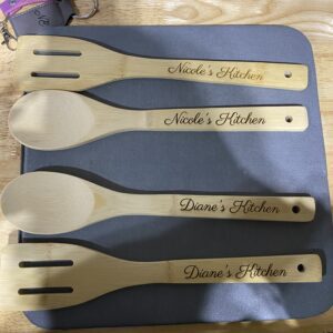 A wooden spoon and fork set with the name nicole 's kitchen engraved on it.