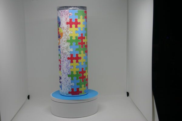 A tall candle with a colorful puzzle pattern on it.